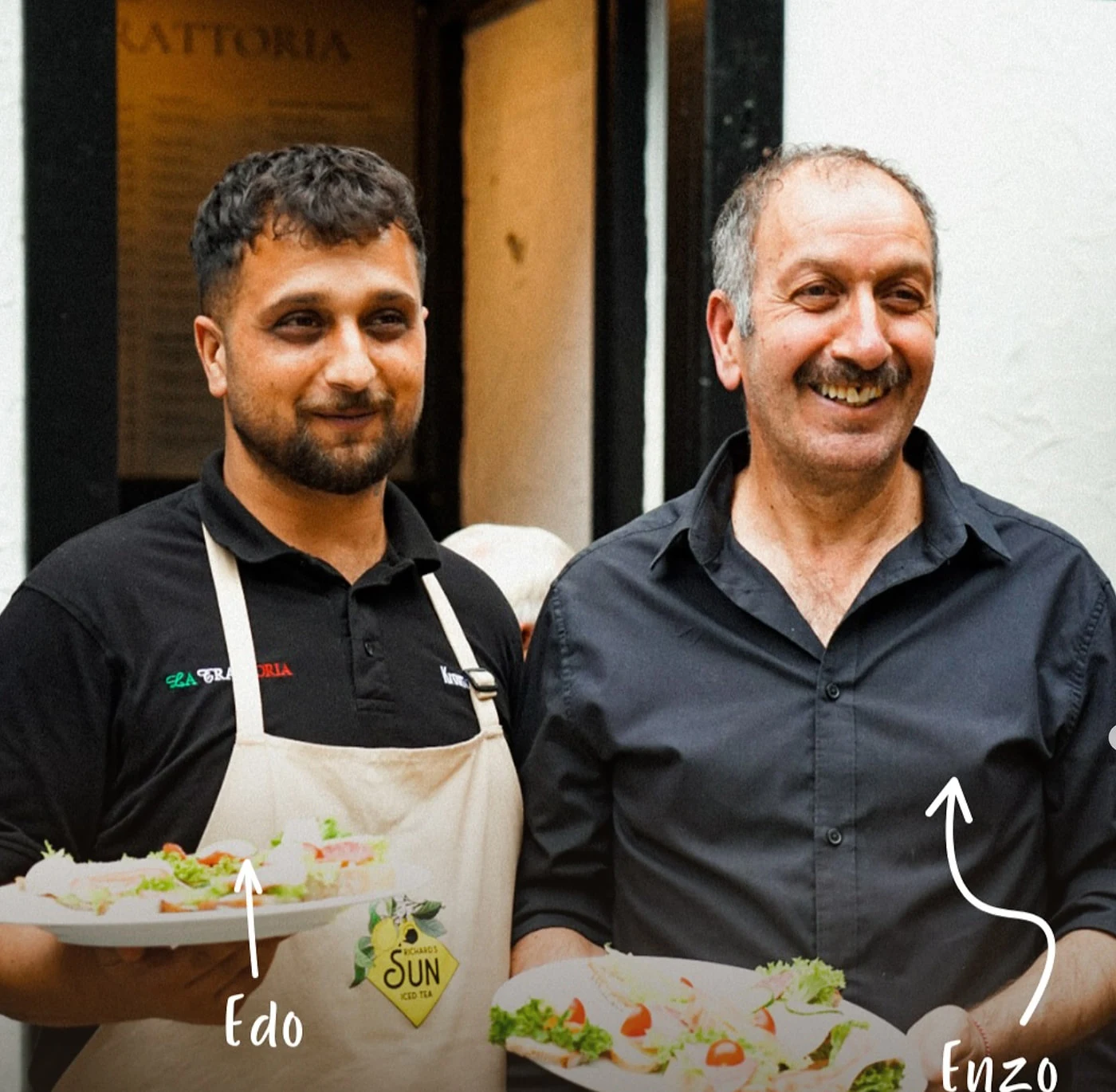 Edo und Enzo Akbulut mit angerichteten Tellern vor dem Eingang von La Trattoria