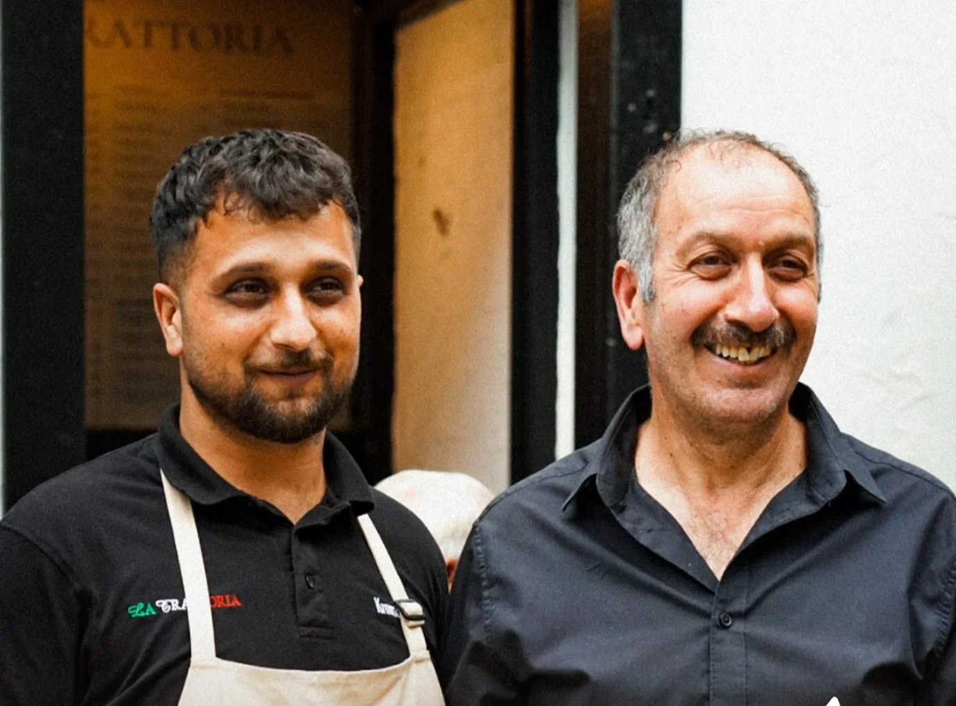 Edo und Enzo Akbulut mit angerichteten Tellern vor dem Eingang des Restaurants