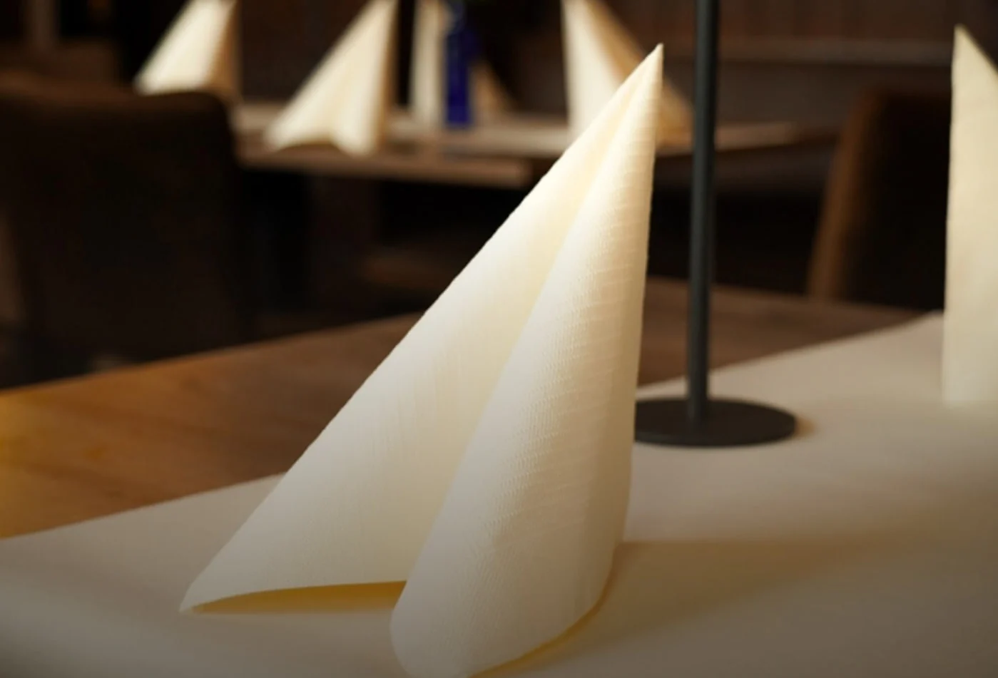 Gefaltete Servietten auf einem eingedeckten Tisch im warmen Abendlicht